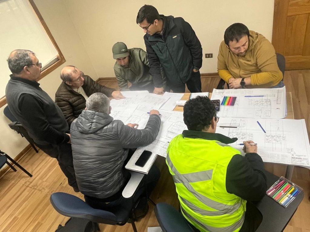 Mantenedores trabajando en grupo sobre los planos del equipo